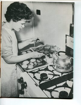 Judith coating biscuits with icing in the kitchen