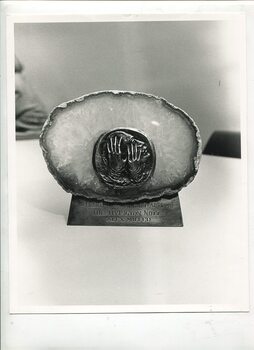 Bronze sculpture of hands touching a face embedded into a large piece of quartz