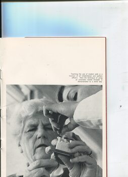 Women watches and feels as another showing her how to thread a needle using a device