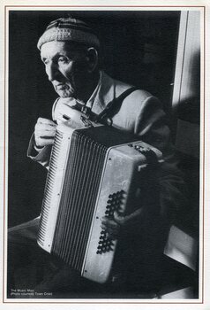 Elderly man holds a piano accordian