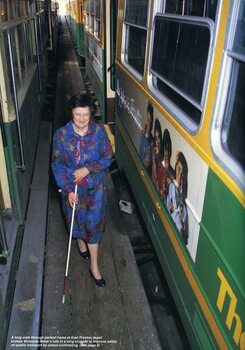 Winsome Baker walks between parked trams at the East Preston depot, using her white cane.