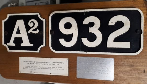 Cast iron train numbers mounted on wood
