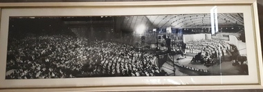 Black and white image of crowd, camera men and stage performers at Carols