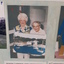 Two women holding a painting of the boatshed at Barwon Heads