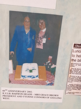 Two women stand with a decorated cake before them