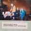 Elderly woman cuts decorated cake whilst three other women look on
