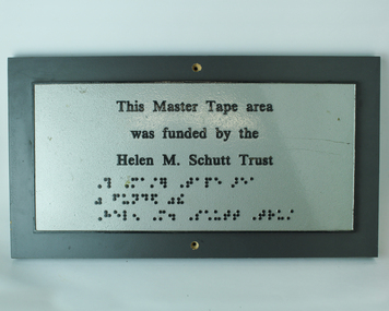 Silver plaque with raised black writing and braille