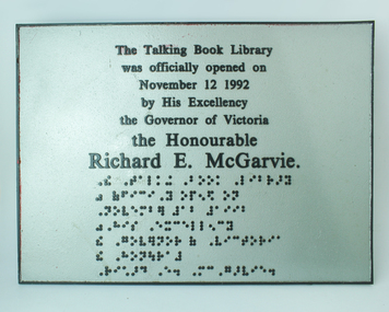 Silver plaque with black raised lettering and braille