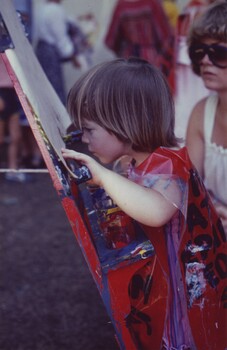 Girl peering closely at a piece of paper as she paints