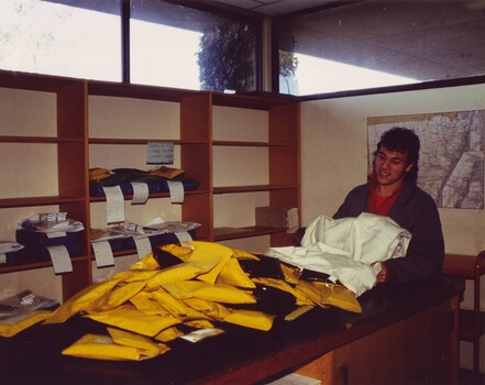 Mailroom employee opening mail bags containing cassette pouches on to a table