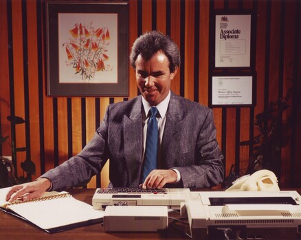 Michael Simpson in his office reading Braille and typing