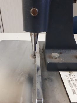 Metal sheet with ridges to align items above a punch activated by a lever pushed downwards