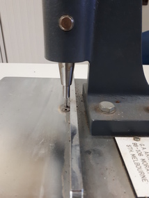 Metal sheet with ridges to align items above a punch activated by a lever pushed downwards