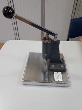 Metal sheet with ridges to align items above a punch activated by a lever pushed downwards