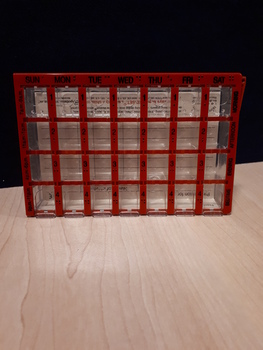 Rectangular container divided into 28 portions with orange cover and black writing