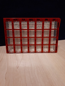 Rectangular container divided into 28 portions with orange cover and black writing