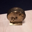 Small brass travel clock with raised dots and steel arms