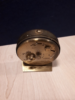 Small brass travel clock with raised dots and steel arms