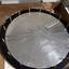 Large metal circle with raised markings and metal shafts around designated edge points. Two metal labels placed casually on top.