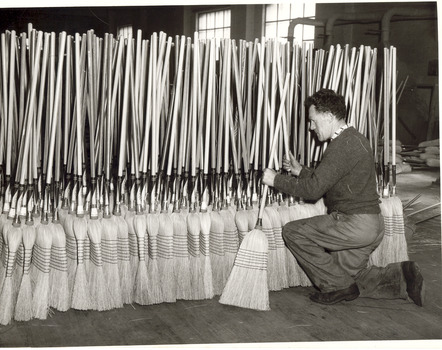 Man stacking finished millet head brooms