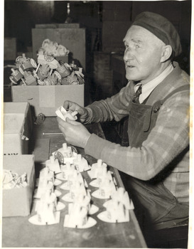 Male sitting as he works on wooden boats