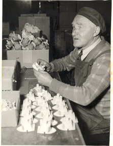 Male sitting as he works on wooden boats
