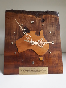 Wooden base with clockface in shape of Australia and plaque beneath