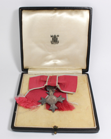 Medal with four points hangs from ribbon inside black box