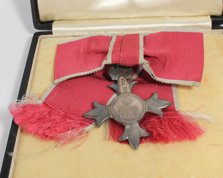 Medal with four points hangs from ribbon inside black box