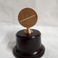 Bronze medallion on brown pedestal with bronze holder