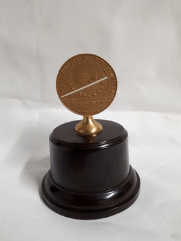 Bronze medallion on brown pedestal with bronze holder