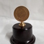 Bronze medallion on brown pedestal with bronze holder