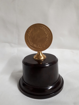 Bronze medallion on brown pedestal with bronze holder