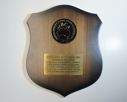 Wooden shield with 1 black NFBCA disk and 1 gold name plate
