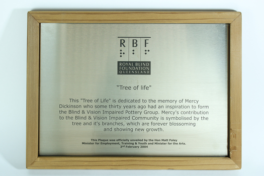 Silver plaque with black writing in wooden frame