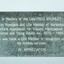 Gray sign with white lettering and four screwholes
