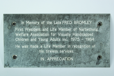 Gray sign with white lettering and four screwholes