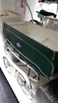 Side view of green pram with white lining and chrome detail