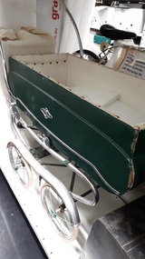 Side view of green pram with white lining and chrome detail