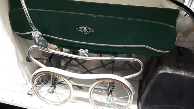 Side view of green pram with white lining and chrome detail
