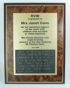 Framed plaque with black writing and Braille