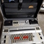 Silver case and keyboard with red, tan and black buttons inside black briefcase