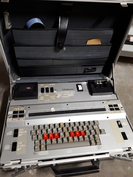 Silver case and keyboard with red, tan and black buttons inside black briefcase