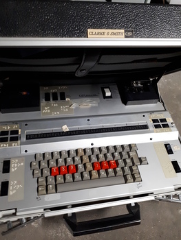 Silver case and keyboard with red, tan and black buttons inside black briefcase
