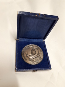 Heavy round coin with a sailing ship on waves with three insignia under it