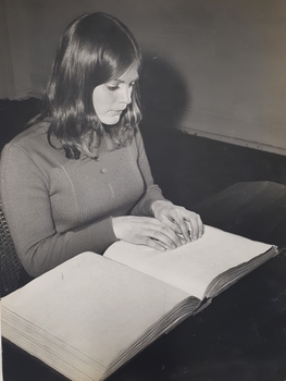 Woman reading Braille book at desk