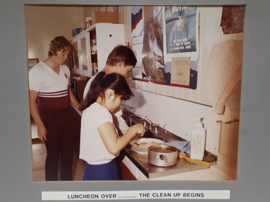 Three teenagers in the kitchen after a meal