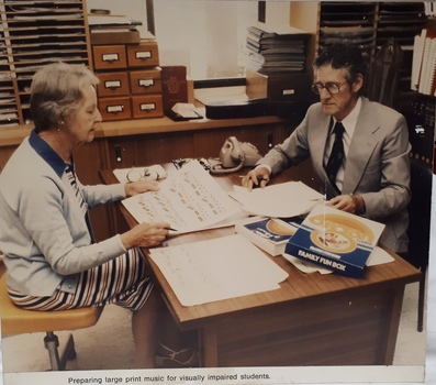 Woman and man look over papers either side of a desk