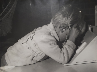 Blonde haired young boy holds the handle whilst peering into the box