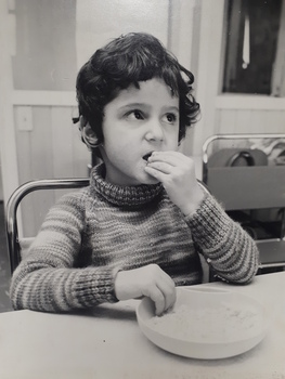 Young boy holds a plate with raised sides and food to his mouth